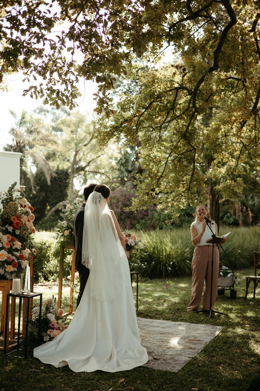 A celebrant speaking during a garden wedding ceremony under an oak tree